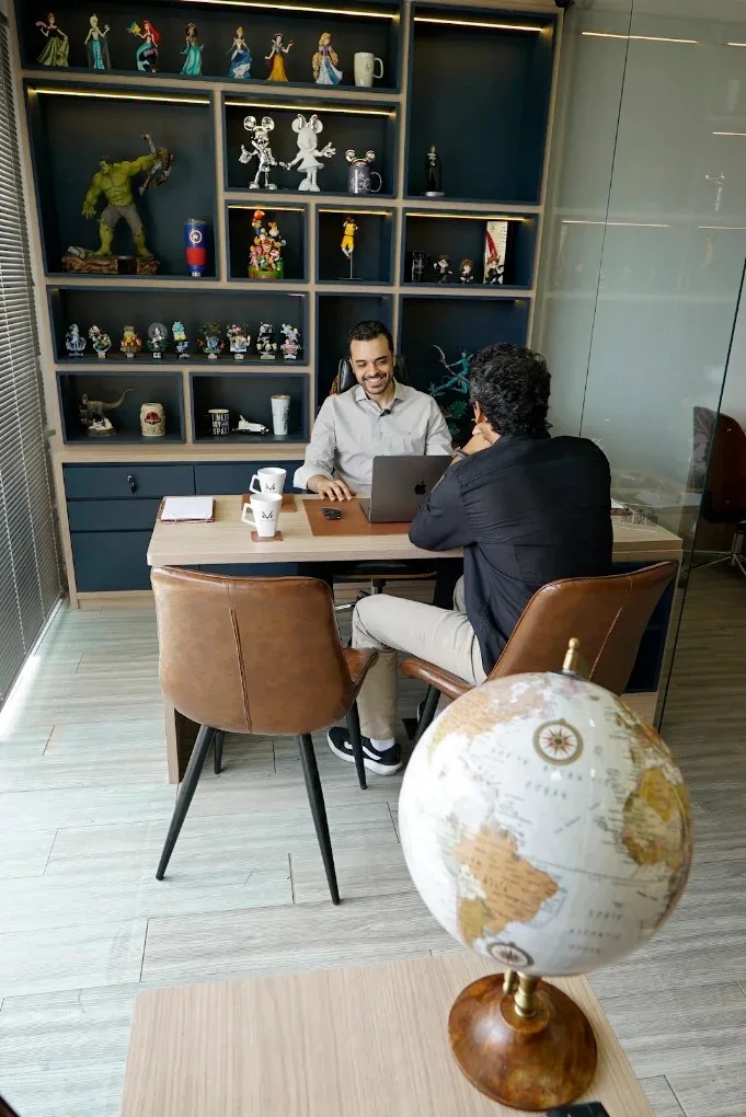 Especialista da MVA Vistos em atendimento consultivo com cliente, em sala de reunião com globo terrestre