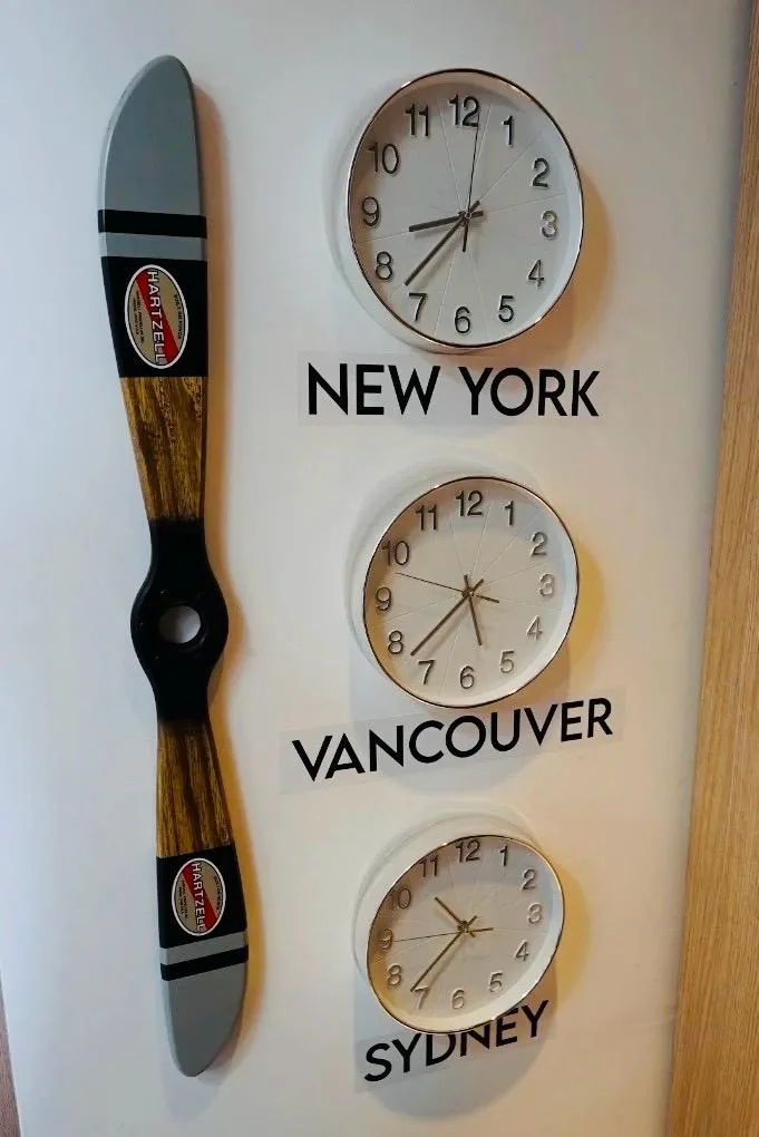 Mural com relógios de Nova York, Vancouver e Sydney, ao lado de uma hélice decorativa, no escritório da MVA Vistos